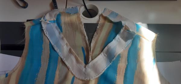 Le "collier" tout autour du col est donc sensé se rabattre à l'intérieur une fois fini.<br><br>Derrière, on peut voir que la robe possède une fente; il s'agit en fait d'une erreur de ma part. La robe n'était pas sensée posséder une fente à l'arrière, mais je croyais que c'était le cas. Du coup, lors de la coupe, j'ai séparé les pans arrière alors qu'ils auraient dû être un pan uni. J'ai dû faire avec, et donc confectionner une fente vers le haut, come visible sur l'image.