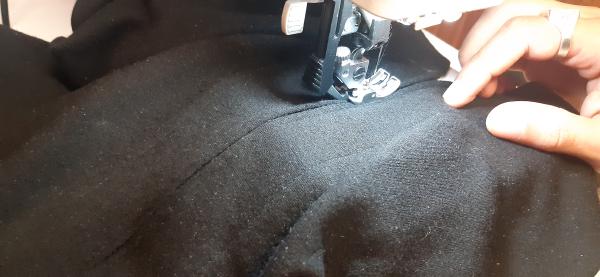 Ici, je suis en train de réduire la longueur de la fente. Mon père et moi-même sommes arrivés à la conclusion qu'elle montait beaucoup trop haut.<br>Pour la réduire, j'ai placé une bande de tissu noir derrière, j'ai rapproché les deux bords, puis je les ai cousus dessus jusqu'à un certain point.